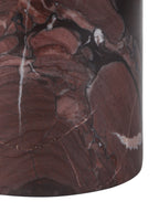 Close-up of the cylindrical marble base, showing red patches, dark lines and pale veins above its curved lower edge.