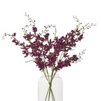 Styled arrangement of deep purple artificial flower sprays in a clear glass vase, with small buds extending above the flowers.