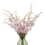 A full arrangement of pale lilac orchid-like flowers and budded branches displayed in a translucent green vase against white.