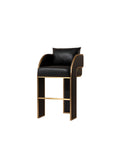 Three-quarter view of a black bar stool with a cushioned seat and back, curved gold-coloured arm outlines, vertically channelled sides and a front footrest.