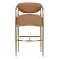 Front view of a cognac upholstered bar stool with an oval back, stitched seat edges, slim gold legs and a curved front footrest on a white background.