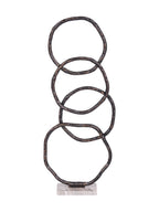 Front view of four overlapping dark, irregular rings standing on a pale rectangular marble base.