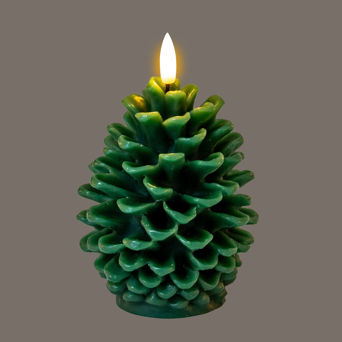 Pinecone LED candle pictured with its flame-shaped element glowing, casting yellow highlights over the upper green scales against a grey background.