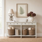 Off-white four-drawer console styled beneath a framed fern print, with a rabbit lamp, floral vase and ornament above baskets and books on the lower shelf.