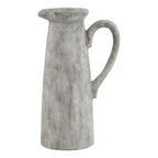 Pale grey-white decorative jug with a tall tapered body, flared spout and long curved handle against a white background.