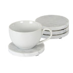 White cup on a pale mottled round coaster, with three matching coasters stacked behind and small black underside pads visible.