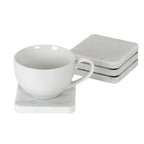 White cup resting on a pale mottled square coaster, with three matching coasters stacked behind it.