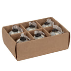 Angled view of pale ribbed baubles arranged in a divided brown tray, with dark caps and white sheer ribbon ties visible above the partitions.