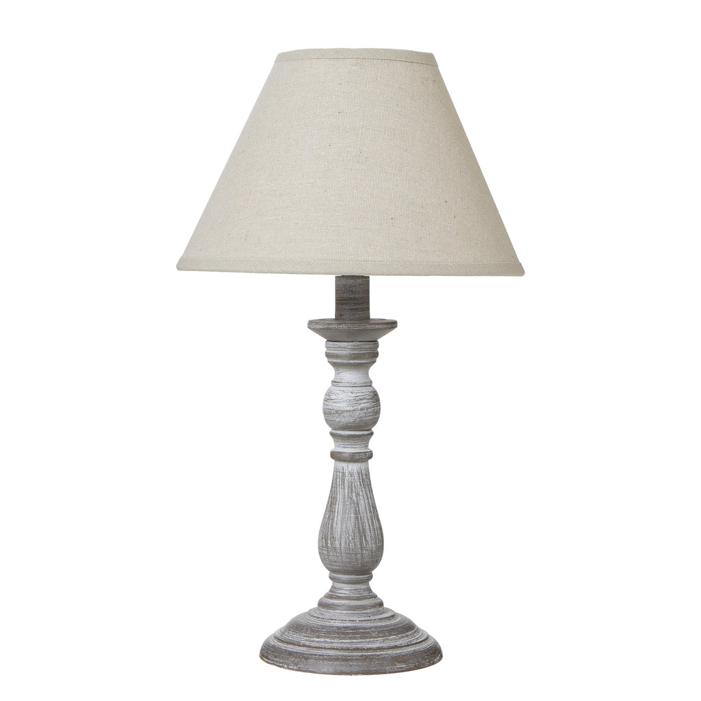 Column table lamp with a tapered neutral shade above a grey-brown base with pale rubbed highlights and a round foot.