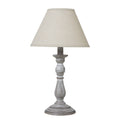 Column table lamp with a tapered neutral shade above a grey-brown base with pale rubbed highlights and a round foot.