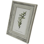Angled front view of the pale layered photo frame, showing the depth of its right edge and a green leafy insert.