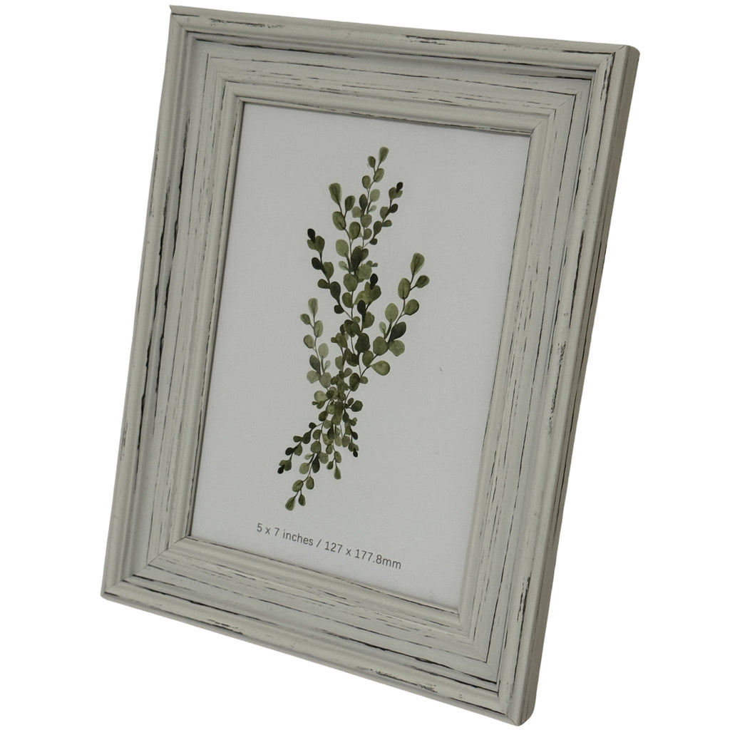 Angled view of the portrait frame showing its stepped pale border, dark rubbed lines and green leafy insert.