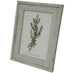 Angled view of the portrait frame showing its stepped pale border, dark rubbed lines and green leafy insert.