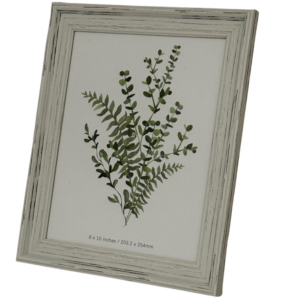Angled front view of the portrait photo frame, showing its stepped pale border, dark rubbed lines and green botanical insert.
