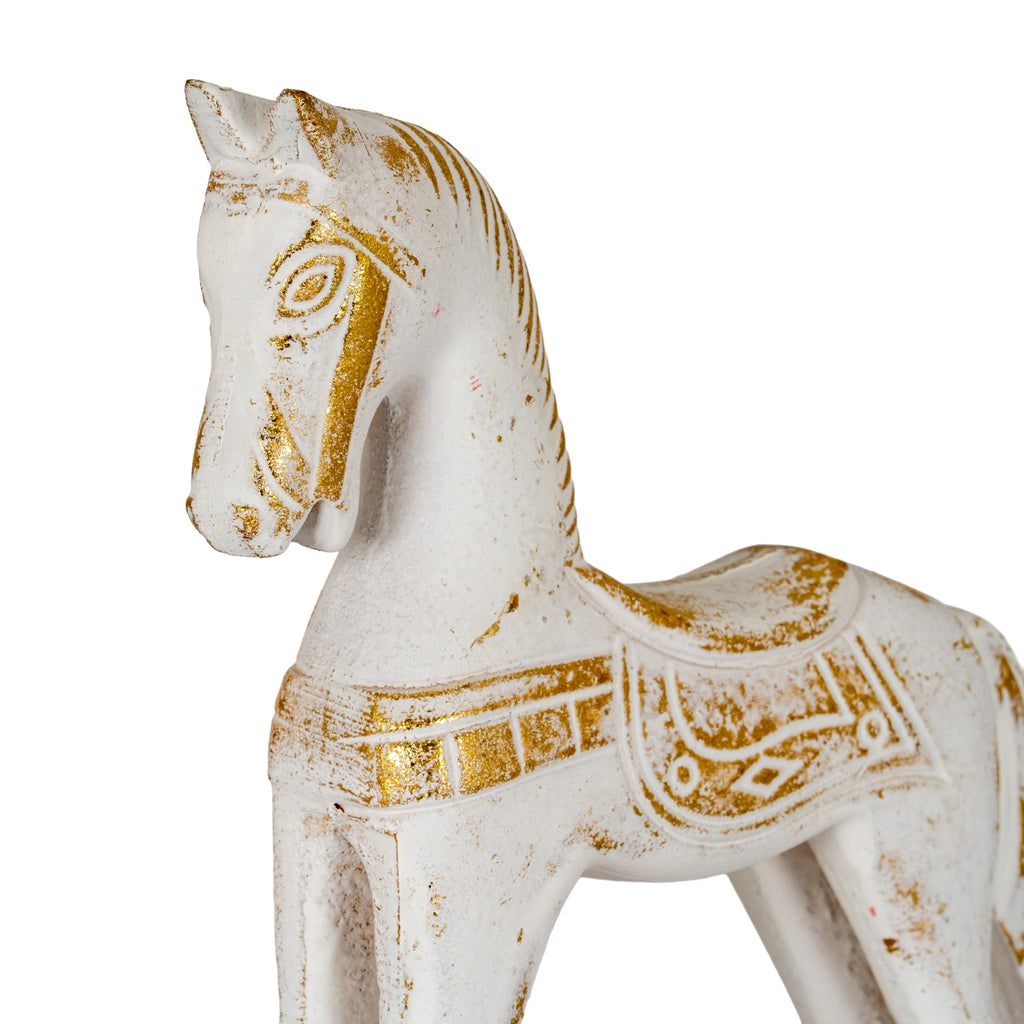 Close-up of the horse's head and saddle, showing gold-coloured facial markings and decorative patterns across the worn-looking pale surface.