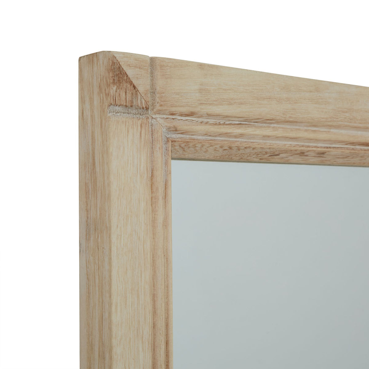 Close-up of the mirror's upper left corner, showing the pale washed finish and warm brown grain-like markings around the reflective face.