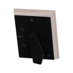 Rear view of the pale photo frame showing its black backing board, two hanging fittings, retaining tabs and extended folding easel stand.