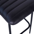 Close-up of the charcoal leather seat showing parallel stitching, rounded edges and part of the black frame.