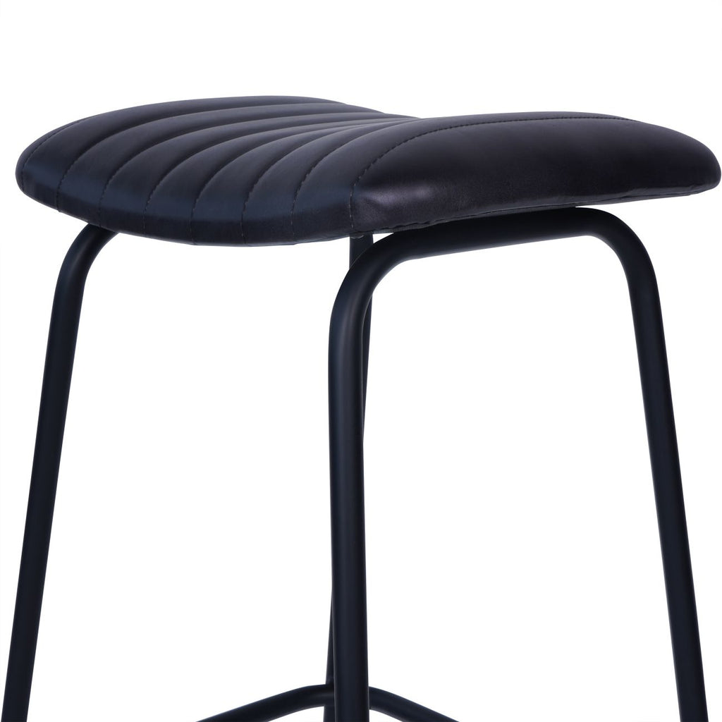 Low angled detail of the curved, channel-stitched charcoal seat above the rounded black leg frame.