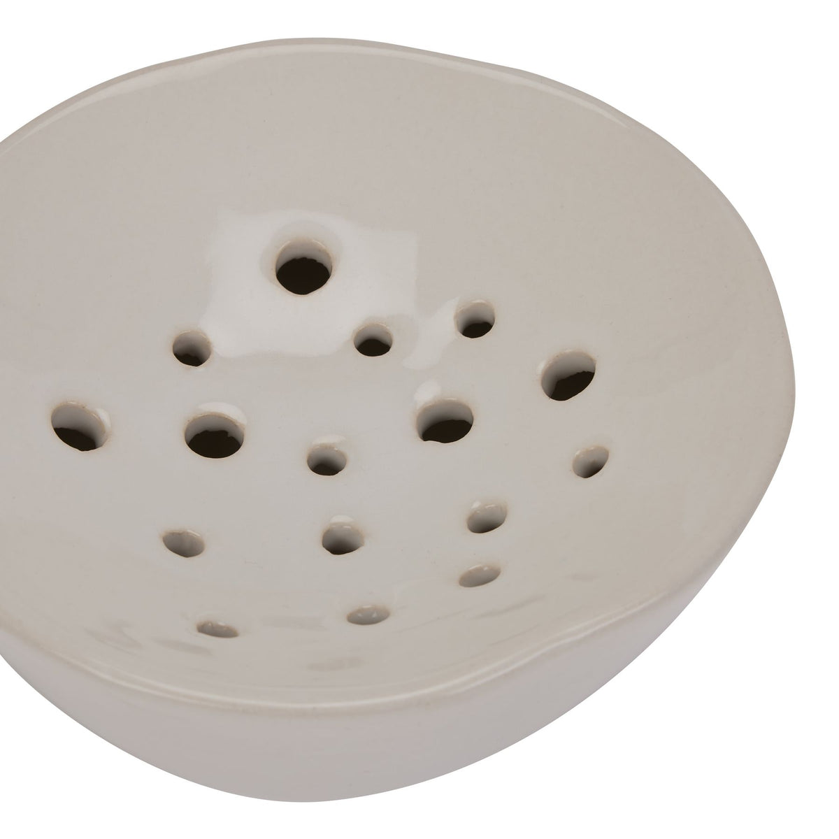 Close-up of the glossy off-white concave top, with different-sized holes scattered inside the gently raised rim.