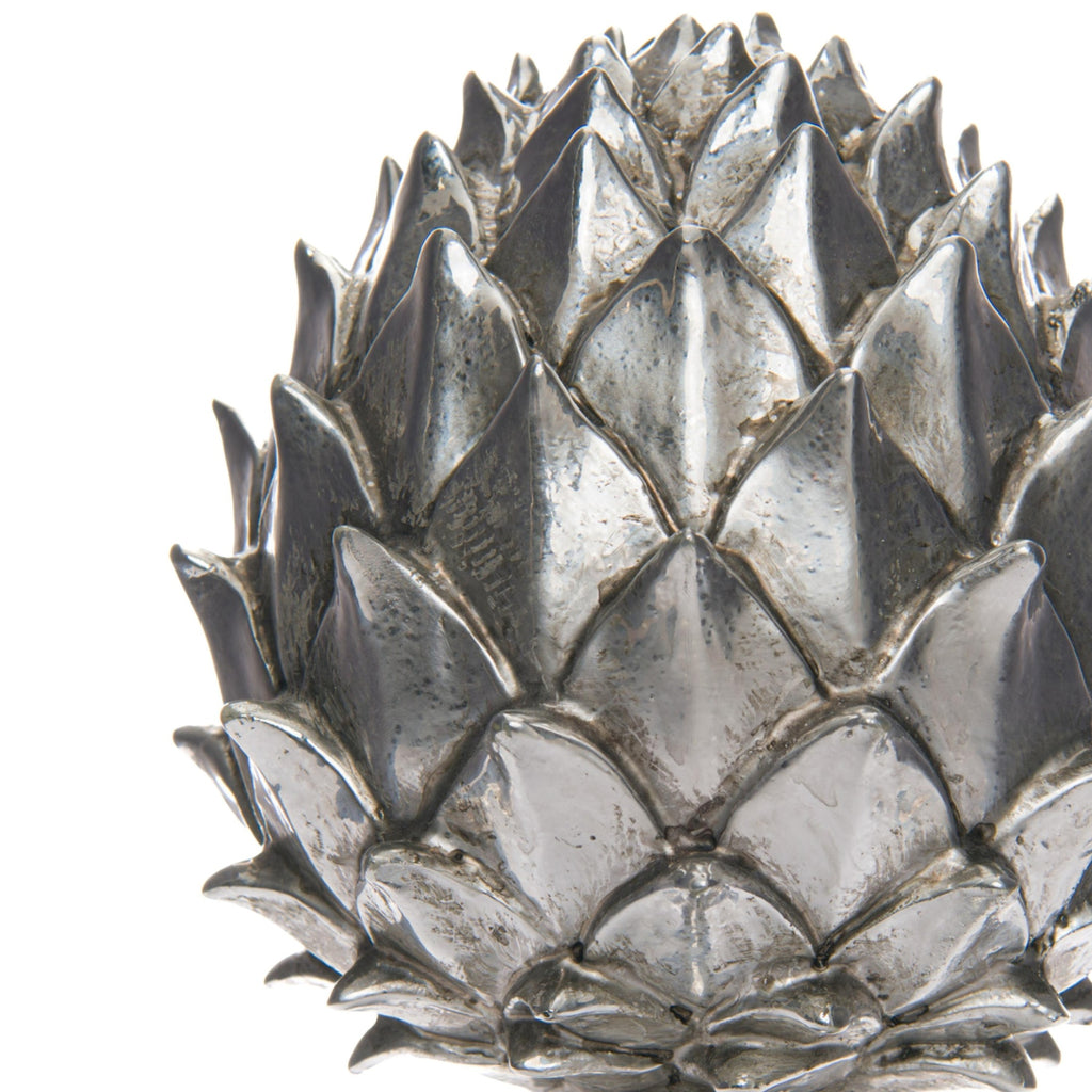 Close-up of the pinecone finial's layered pointed scales, showing bright silver-coloured ridges and darker mottled recesses.
