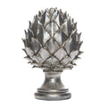 Silver-coloured pinecone finial with overlapping pointed scales, a narrow neck and rounded stepped pedestal base on a white background.
