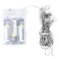 Coiled silver-coloured light wire beside a clear battery box with batteries visible inside, on a white background.