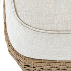 Close-up of the pale beige cushion's textured surface and piped rounded corner, with the brown patterned base below.