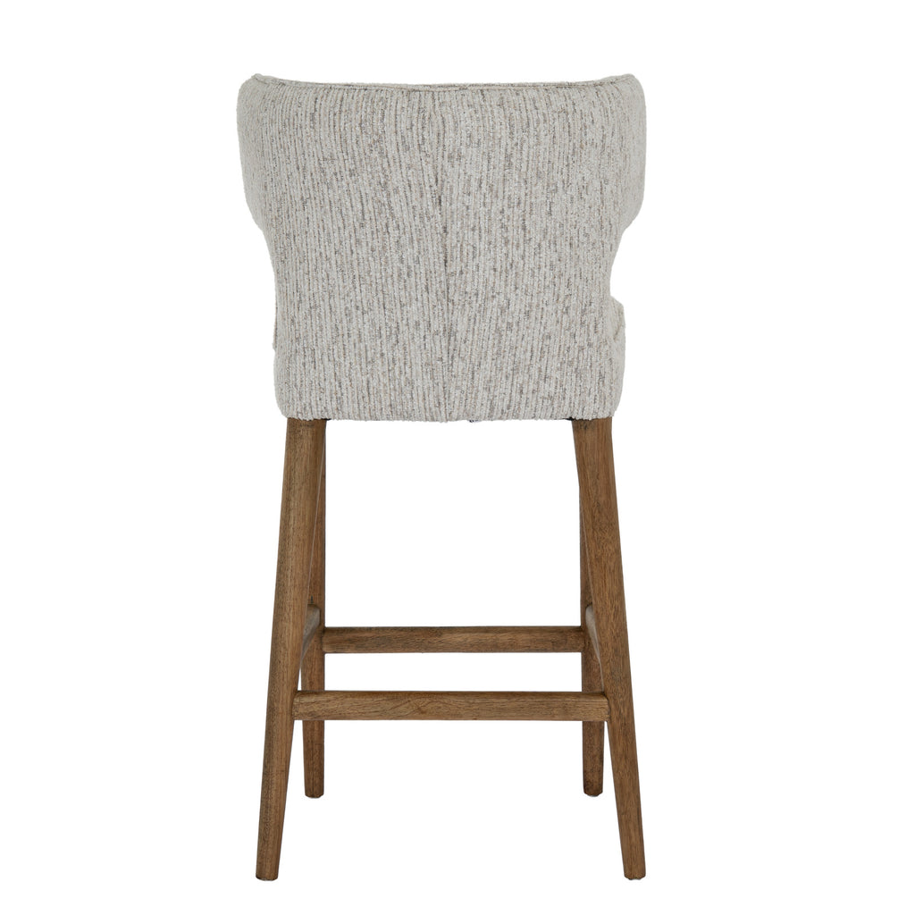 Rear view of the bar stool with a broad curved upholstered back, central seam and warm-brown legs joined by horizontal stretchers.