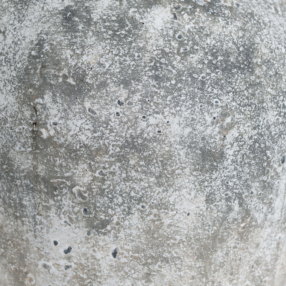 Close-up of the vase's irregular pale mottling, dark pits and earthy patches.