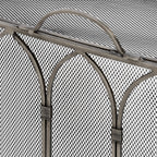 Close-up of the fire screen's curved handle, pointed metal arches and wrapped collars against fine diamond mesh.
