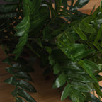 Close-up of pointed artificial green leaflets with lighter central veins and a slight sheen, layered over branching stems.