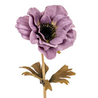 Close-up of the artificial purple flower, showing overlapping textured petals, a dark round centre and the upper stem with leaves.