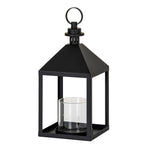 Three-quarter view of a black candle lantern with a square base, four upright posts, clear cylindrical inner holder and pyramidal top beneath a round ring.