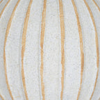 Close-up of the ball's speckled cream-white surface and tan grooves with gently uneven edges.