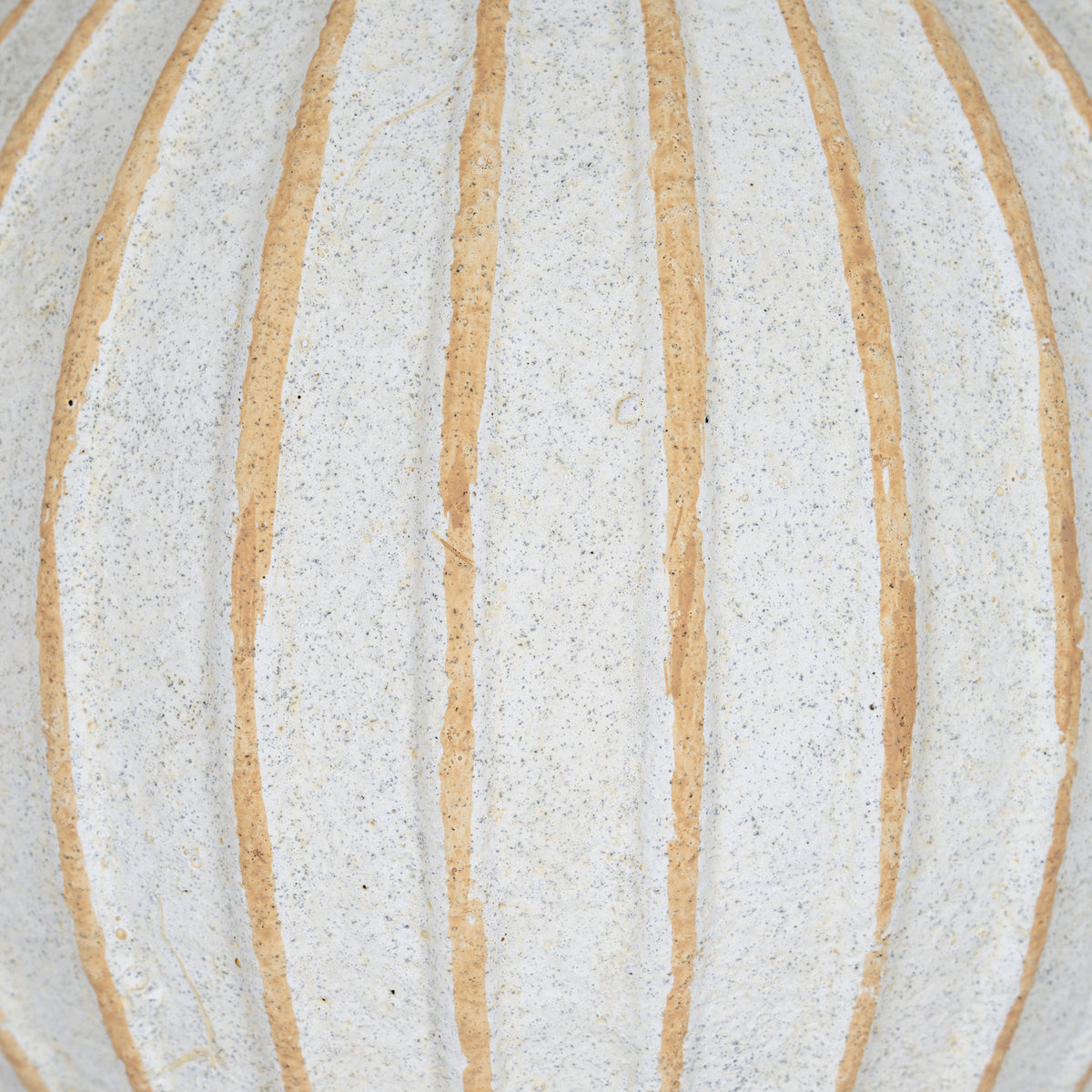 Close-up of the ball's speckled cream-white surface and tan grooves with gently uneven edges.