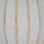 Surface detail of the vase showing uneven tan grooves across the granular, finely speckled cream-white body.