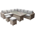 Woven L-shaped corner seating with pale cushions and raised end arms, shown with a higher rectangular table and two square cushioned stools on white.
