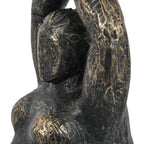 Close-up of the figure's simplified face, sculpted hair and raised arm showing the rough distressed bronze finish.