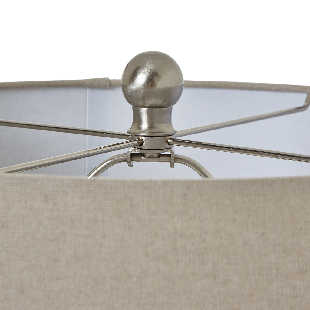 Detail of the silver-toned rounded finial and crossing supports inside the pale woven-texture lamp shade.