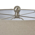 Detail of the silver-toned rounded finial and crossing supports inside the pale woven-texture lamp shade.