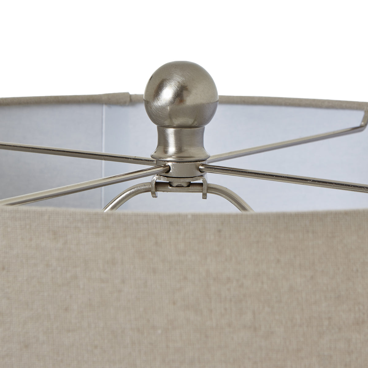Detail of the silver-toned rounded finial and crossing supports inside the pale woven-texture lamp shade.