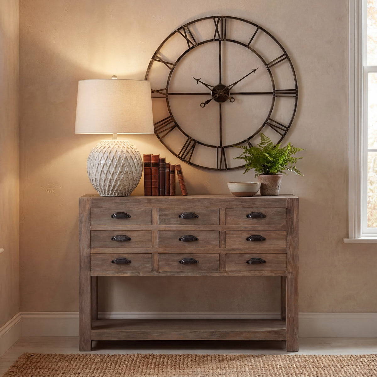 Diamond patterned table lamp styled on a console beside books, a bowl and potted greenery, beneath a round wall clock.