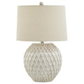 Pale table lamp with a rounded diamond lattice base, tapered cream shade and round metallic-looking finial against white.