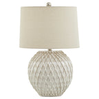 Pale table lamp with a rounded diamond lattice base, tapered cream shade and round metallic-looking finial against white.