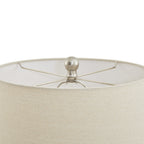 View into the open top of the pale lampshade, showing crossed supports and the round metallic-looking finial.