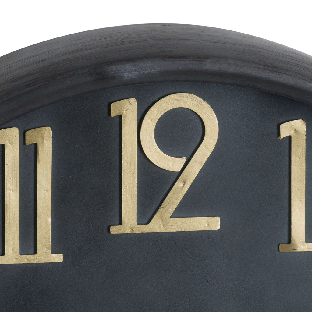 Close-up of the raised numeral twelve, showing fine surface markings in its gold-toned finish against the black clock face.