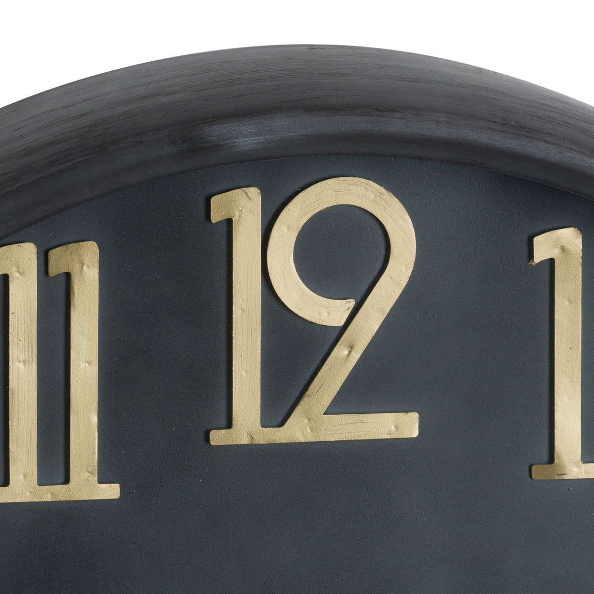 Close-up of the raised numeral twelve, showing fine surface markings in its gold-toned finish against the black clock face.