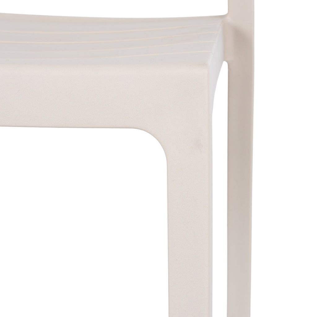 Close-up of the pale putty chair's seat edge and front leg, showing the fine pebbled texture and rounded inner corner.