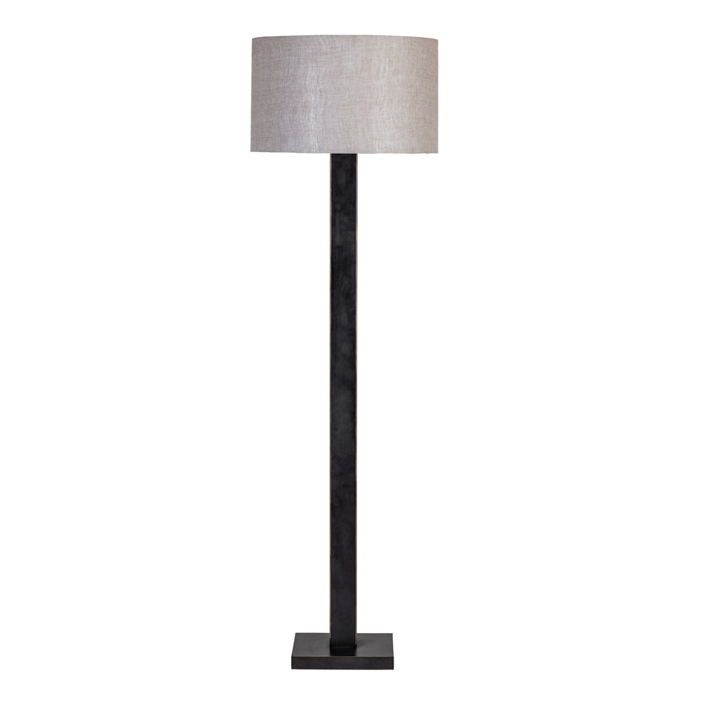 Front view of the floor lamp with a natural fabric drum shade, dark rectangular stem and square base against white.
